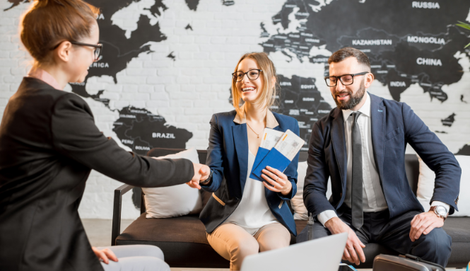 Three professionals shaking hands in a modern office with a world map on the wall.