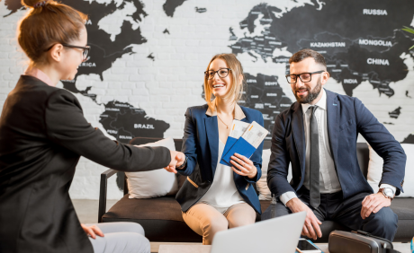 Three professionals shaking hands in front of a world map wall decor.
