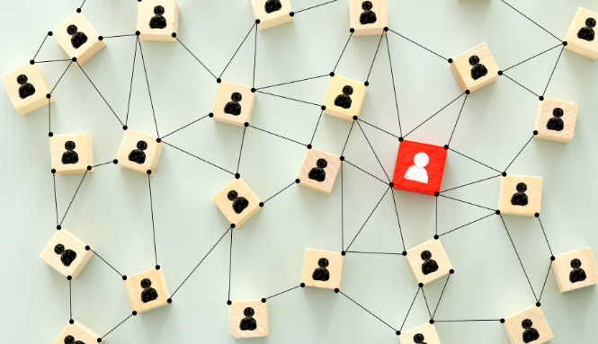 Network of wooden blocks with people icons connected by lines, one red block in center.